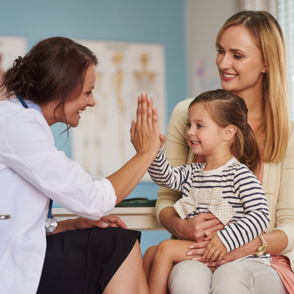 Cirurgia de adenoide quando fazer: doutora sorrindo para pciente criança e sua mãe.